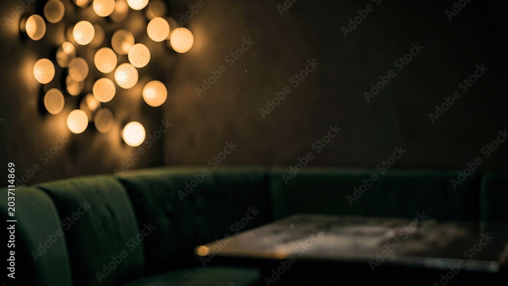 Fototapeta premium Plush velvet seating and dark wood surface against warm golden bokeh glow
