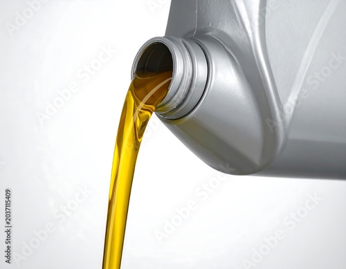 Close-up of a container pouring yellow liquid onto a white background, highlighting the flow and color contrast