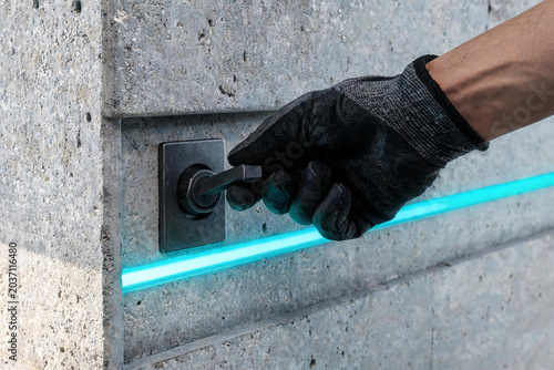 Gloved hand activating industrial lever on concrete wall