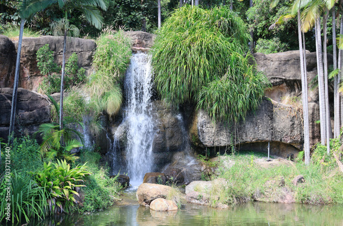 A beautiful man-made waterfall flowing over rocky cliffs into a pond at Kershaw Gardens in Rockhampton, Queensland, Australia