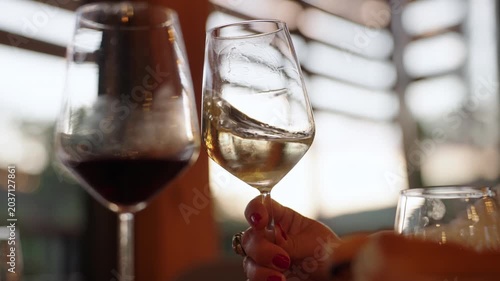 Glasses of red and white wine raised together smelled in warm restaurant light