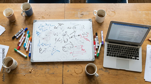 Busy Desk Brainstorming: Overhead View of Whiteboard, Laptop, and Coffee Cups