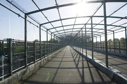 Valokuva Symmetrical caged bridge footbridge with steel mesh security canopy over a pedestrian walkway