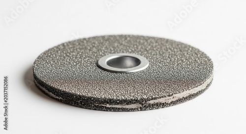 Close-up of a metal grinding disc with a central hole on a white background.
