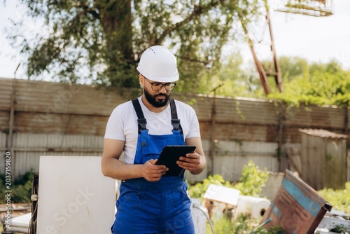 Tableau sur toile Worker using tablet overseeing waste management in junkyard