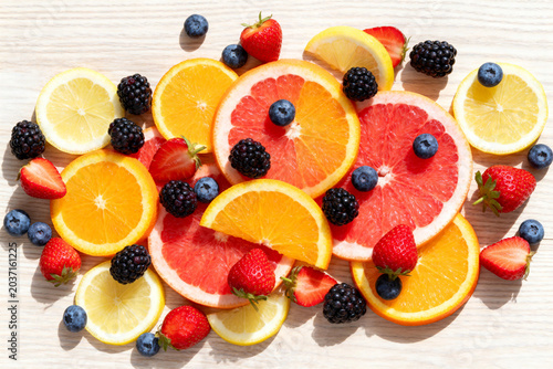 Fresh Mixed Citrus Slices and Berries on Light Wooden Surface
