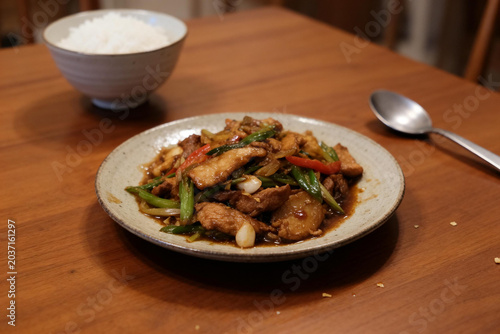 Stir-fried meat and vegetables with soy sauce on plate with bowl of white rice