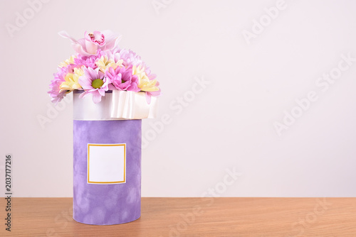 Bouquet of various flowers in a plush gift box on the wooden table. Copy space.