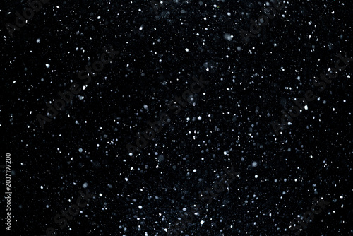 Snow particles drifting across black background. Snow overlay with heavy snowfall. Realistic winter flurry motion. Snowflakes creating abstract pattern. Snowstorm layer with floating particles.