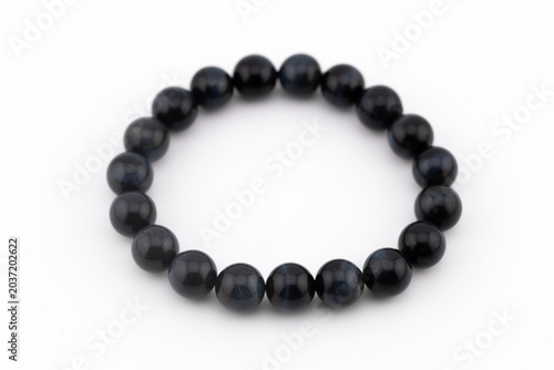 A blue tiger eye natural stone bracelet shows smooth gemstones arranged in a circular pattern. The background is white, highlighting the color and design of the bracelet.