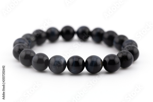 A blue tiger eye natural stone bracelet shows smooth gemstones arranged in a circular pattern. The background is white, highlighting the color and design of the bracelet.