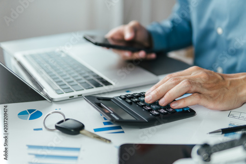 A male accountant calculating annual car tax  income and expense calculations  and analyzing trading reports  concepts of annual vehicle tax  and financial and tax systems.
