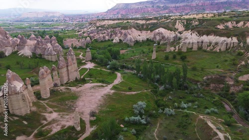 drone aerial flight looking at towering fairy chimney rock pillars and winding dirt paths inside Love Valley. Spectacular geological wilderness landscape in Cappadocia, Turkey 