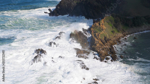 Foto Aerial View of Powerful Ocean Waves Crashing Against Byron Bay Cliffs