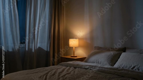 Cozy bedroom with soft lighting and light drapes creating a tranquil nighttime atmosphere