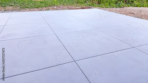 Smooth gray concrete surface with visible joints and a grassy area in the background