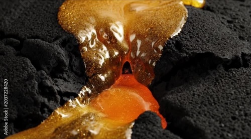 Molten lava flows through dark volcanic rock formations slowly