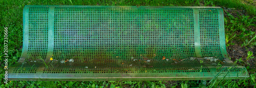 banc public en métal perforé dans l'herbe