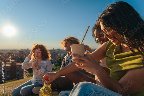 Diverse friends enjoying picnic outdoors watching city sunset