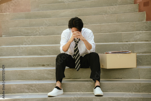 Foto Unemployed professional sitting with a resume and personal belongings after being laid off, expressing stress, career uncertainty, financial concerns, and job search challenges