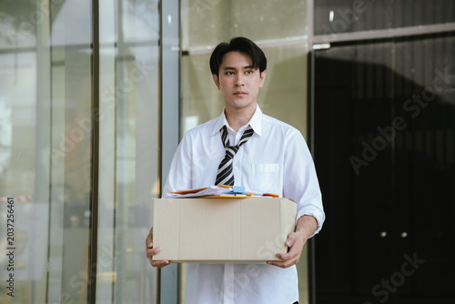 Bild auf Leinwand Former employee carrying a box of personal belongings after job termination, symbolizing unemployment, workforce reduction, career transition, and economic uncertainty