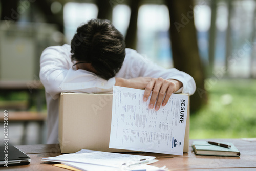 Foto Unemployed professional leaning on a box with a resume in hand, expressing job loss, emotional stress, career uncertainty, and the challenges of finding new employment