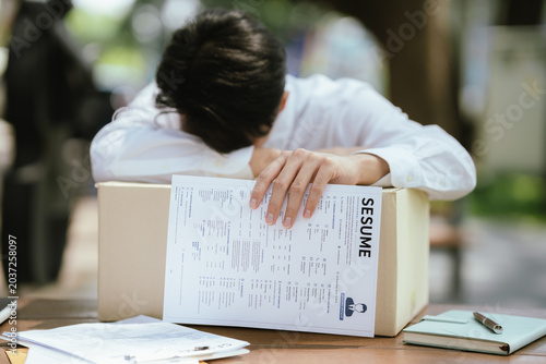 Bild auf Leinwand Unemployed professional leaning on a box with a resume in hand, expressing job loss, emotional stress, career uncertainty, and the challenges of finding new employment