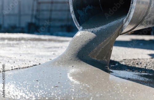 Industrial Concrete Pouring for Building Foundation at a Construction Site. Wet Cement Flowing from a Pipe for Infrastructure Development and Professional Ground Paving Workflow.