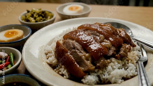 A delicious plate of succulent glazed meat served over fragrant rice, accompanied by vibrant side dishes and garnishes