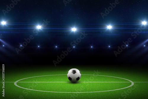 Football stadium illuminated by powerful floodlights with green grass field and soccer ball. Football stadium with floodlights. Soccer tournament, world championship, european football.