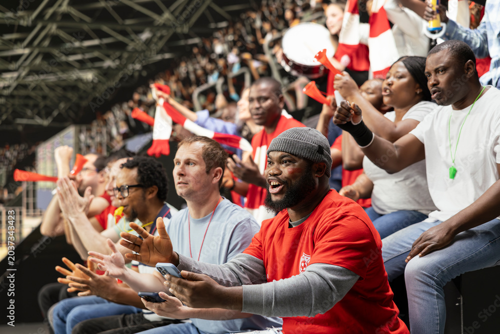 Obraz premium Black football fan excited about big win and team victory at the stadium, successful bet winning ticket on phone. Celebrating a successful cash out and gambling win with crowd excitement.