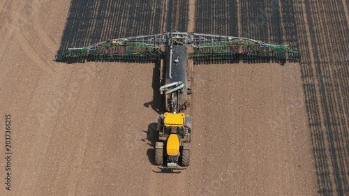 Tractor applying liquid organic manure fertilizer in agricultural field. Precision farming machinery improving soil fertility, crop yield, farm productivity. Sustainable agriculture, agribusiness