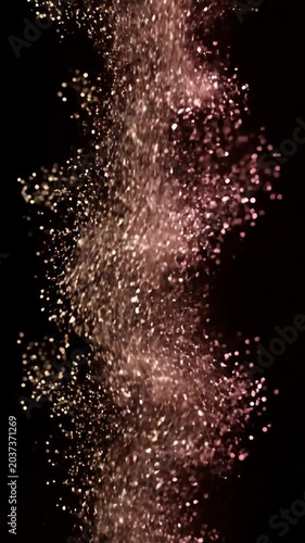 Sparkling particles falling into dark liquid with bokeh.