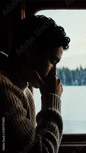 Traveler looking through window at snowy winter forest.