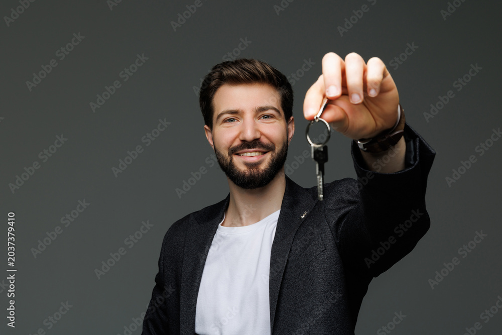 Φωτογραφία Young business man show new home keys on gray background