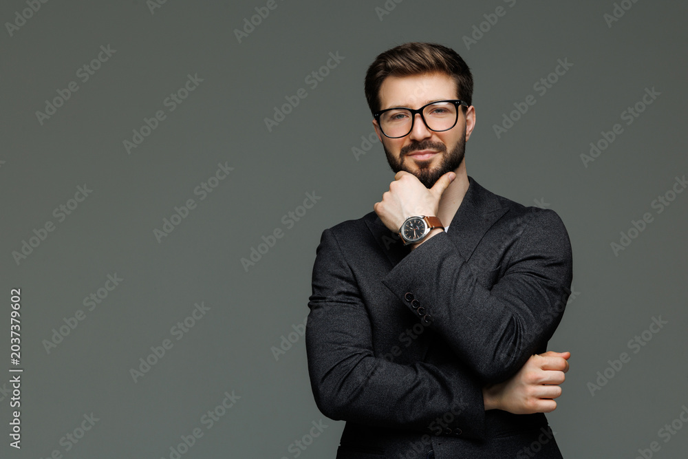 Behang Young business man with hands on chin isolated on gray background