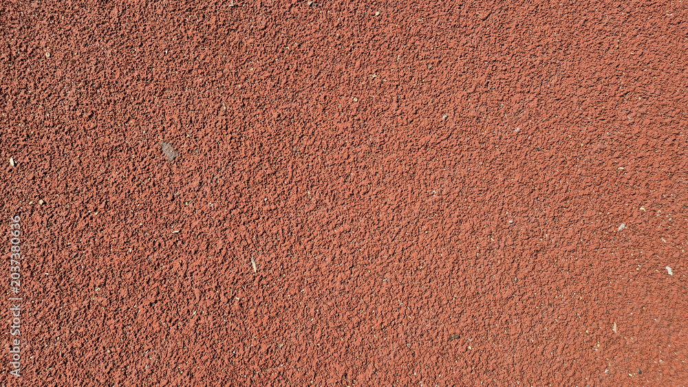 Fototapeta premium ​A close-up shot of a textured, reddish-brown synthetic running track surface.