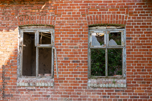 Foto Broken windows in abandoned red brick building facade