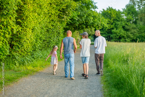 multi-generational family grandfathers, teen boy, little girl walking, Loving family fathers children walking together along trail in green European nature park, enjoying outdoor weekend recreation