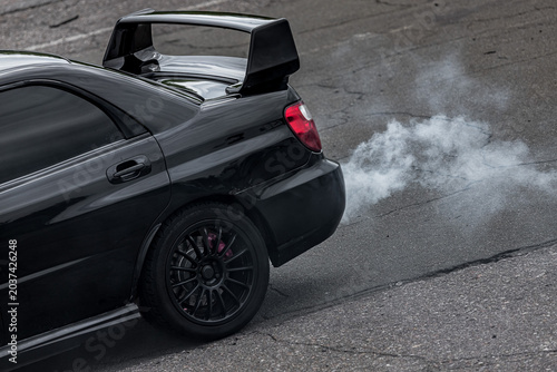Schilderij op canvas Black sports car with exhaust smoke
