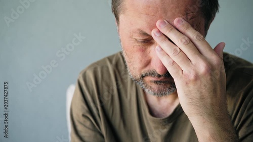 Middle-aged man suffering from headache and stress holding his temple in pain close-up portrait, 4K