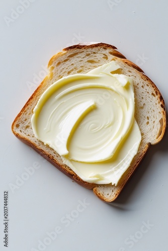 Slice of bread with creamy butter spread, simple breakfast food isolated on clean white background