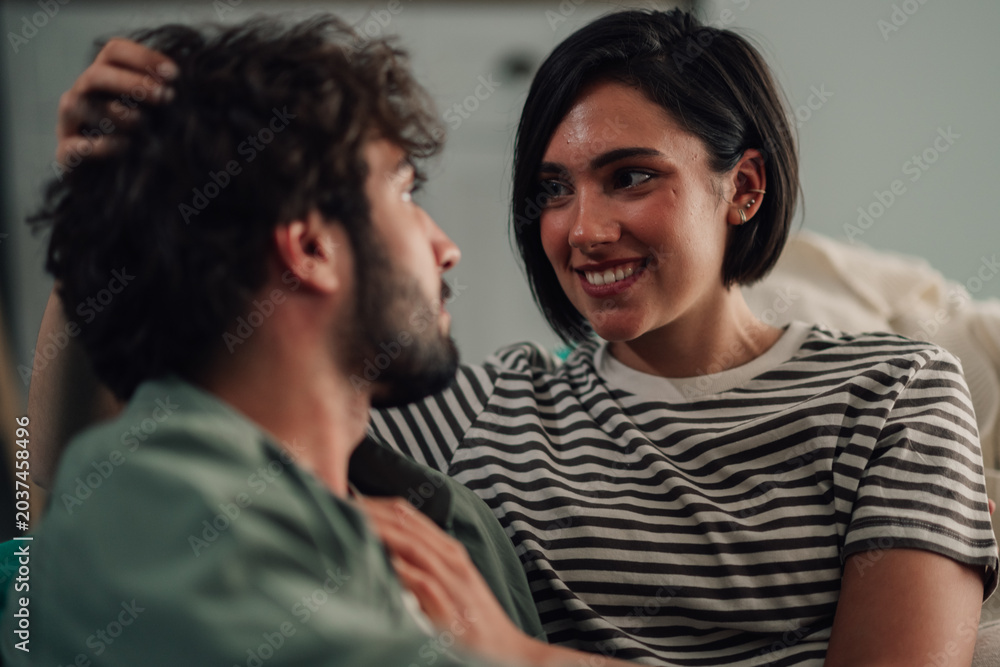 Obraz premium Young couple displaying love and affection while relaxing at home, enjoying an intimate and happy moment together