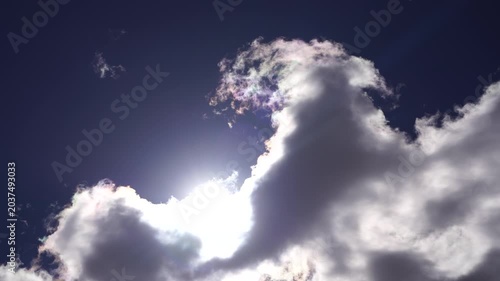 Sun shining behind dark rain clouds in blue sky. Weather and climate concept. Nature sky photography.