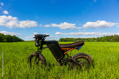 Foto Modern electric fat bike with full suspension standing in a vibrant green meadow