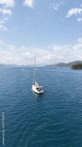 Sailing yacht glides across calm blue ocean waters near lush green islands