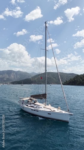 Sailing yacht glides across tranquil blue waters near lush green coastline