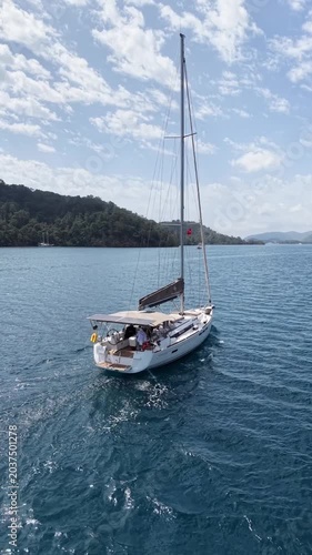 Sailing yacht glides across tranquil blue waters near lush green coastline