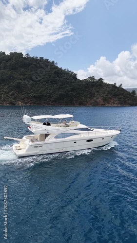 Sailing yacht glides across tranquil blue waters near lush green coastline