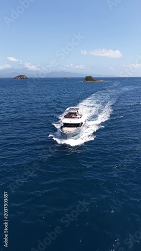Sailing yacht glides across tranquil blue waters near lush green coastline